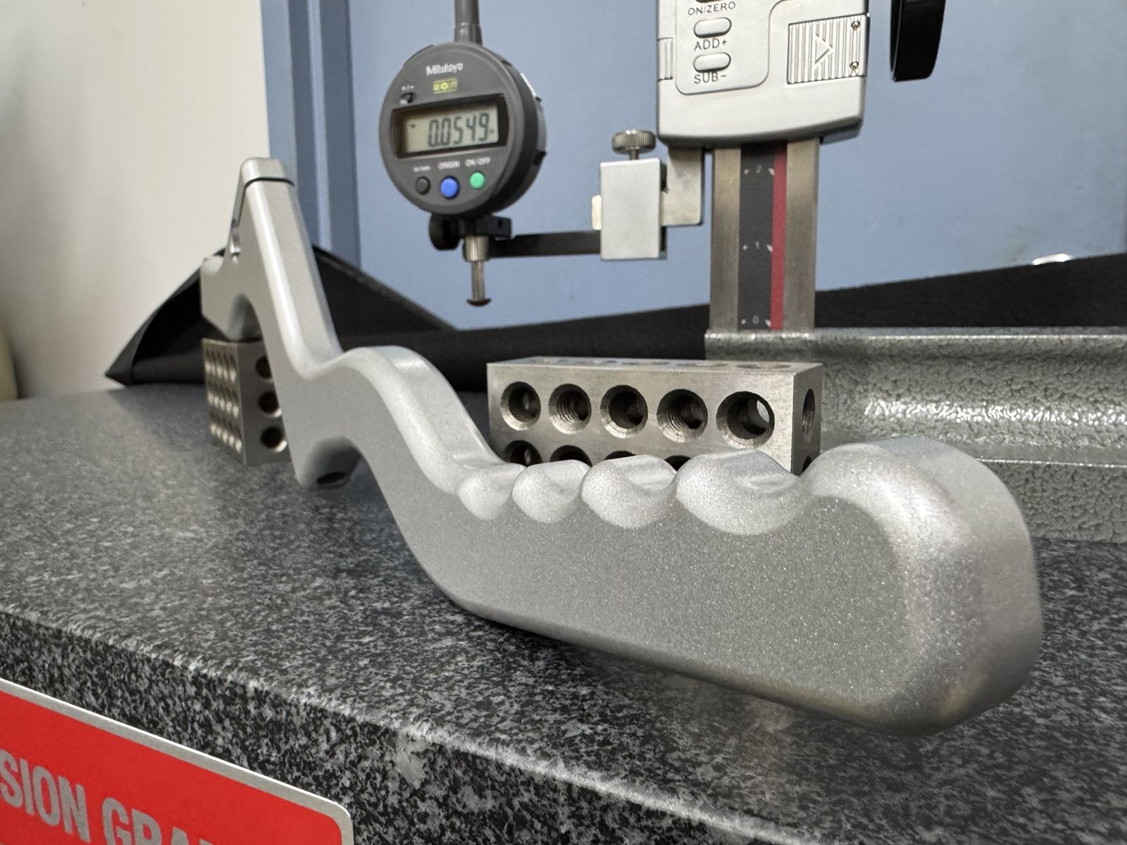 Machined handle checked with a Mitutoyo indicator on a granite surface plate