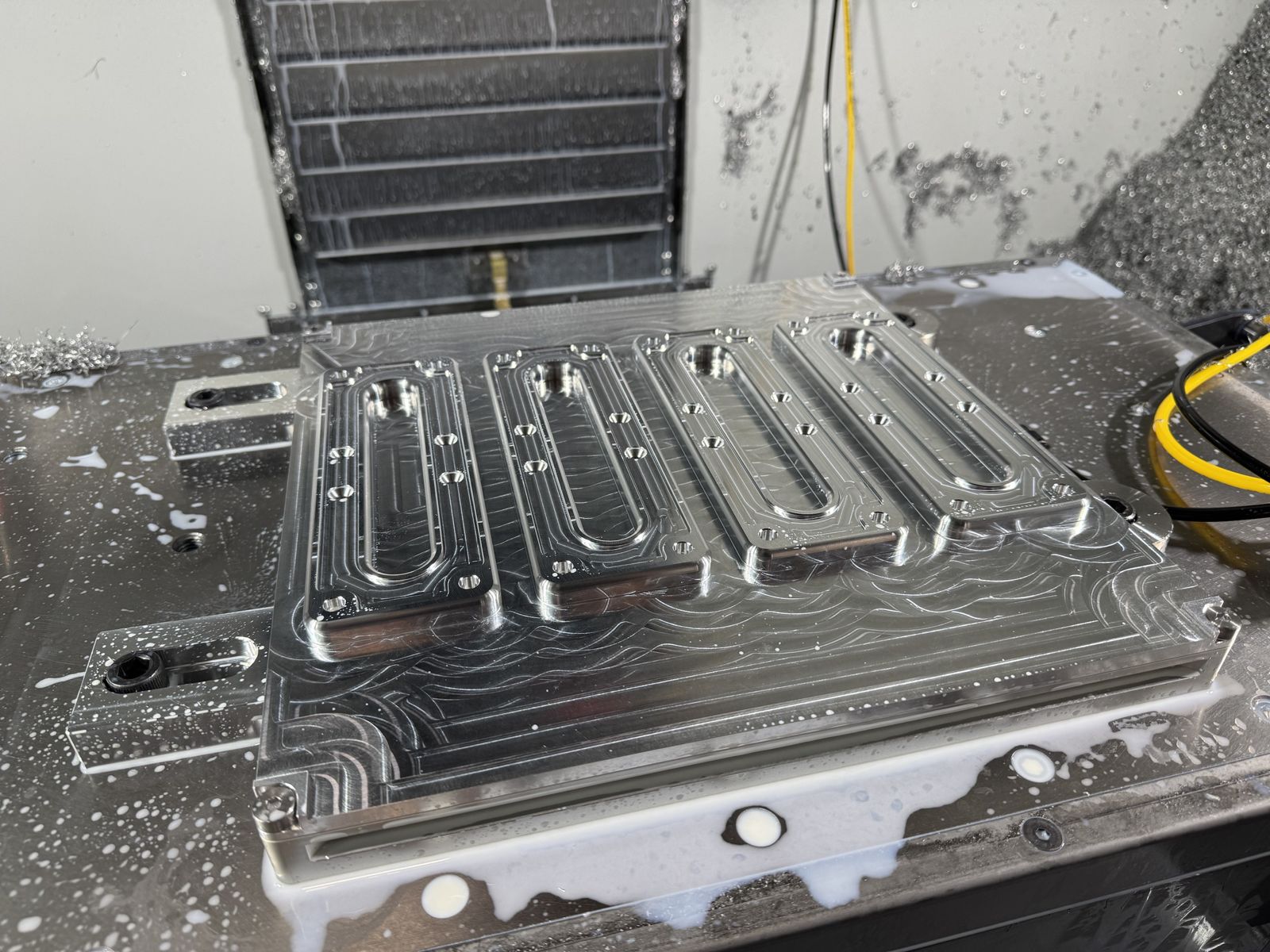 Large aluminum plate with machined pockets on a CNC mill table