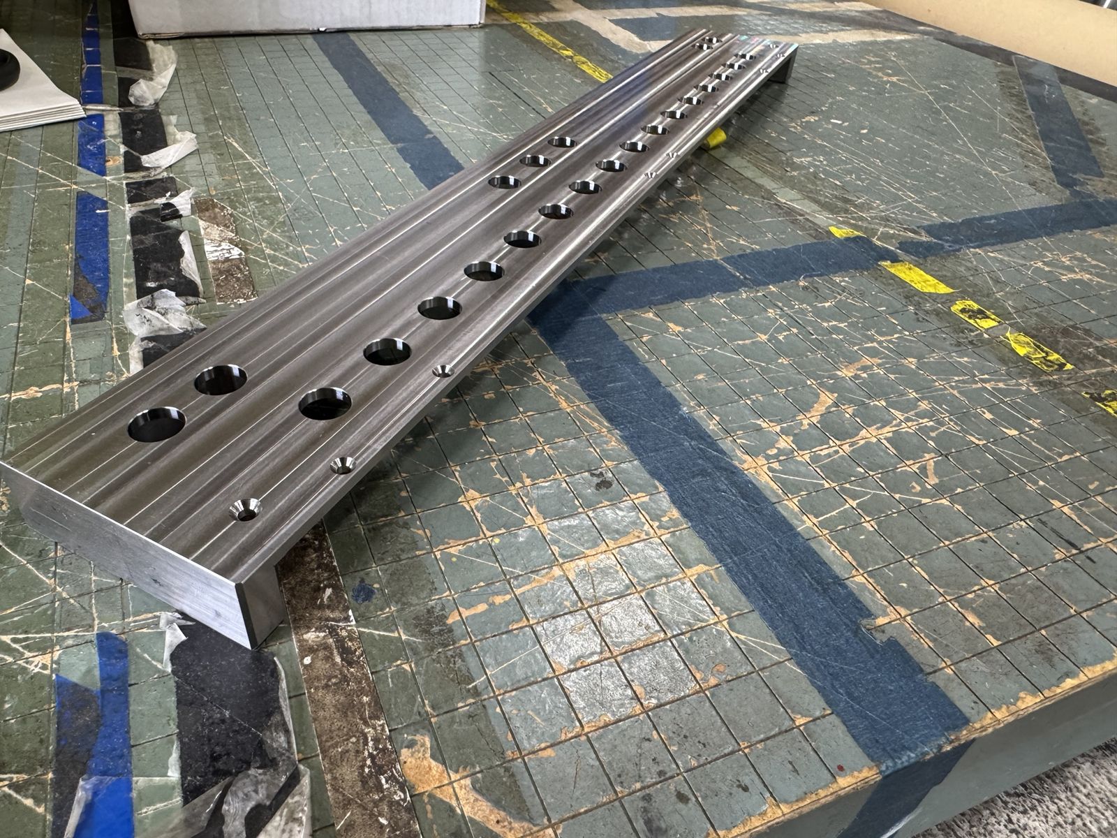 Long machined steel rail with counterbored holes