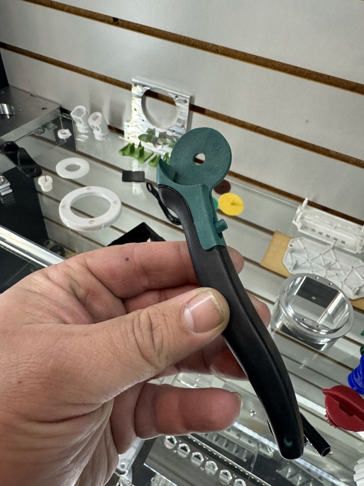 Two-color molded handle held in hand in front of a parts display